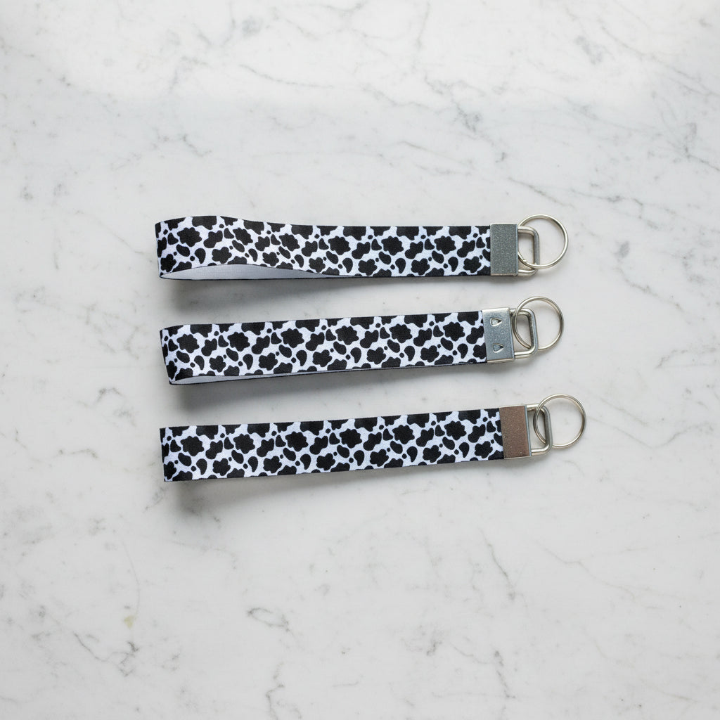 Three black and white patterned keychains on a marble surface